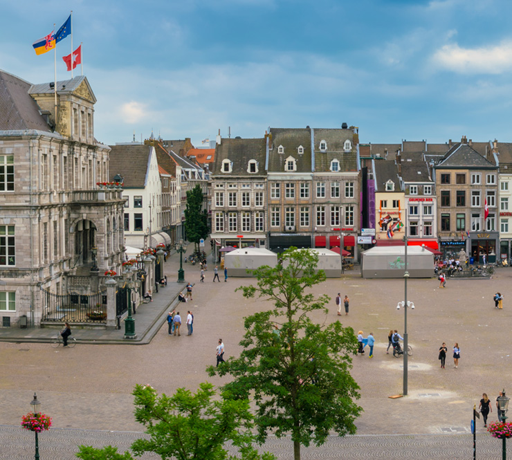 Tourist and locals wander around on the historic Market Square with the Town Hall in the center of town in Maastricht, Netherlands