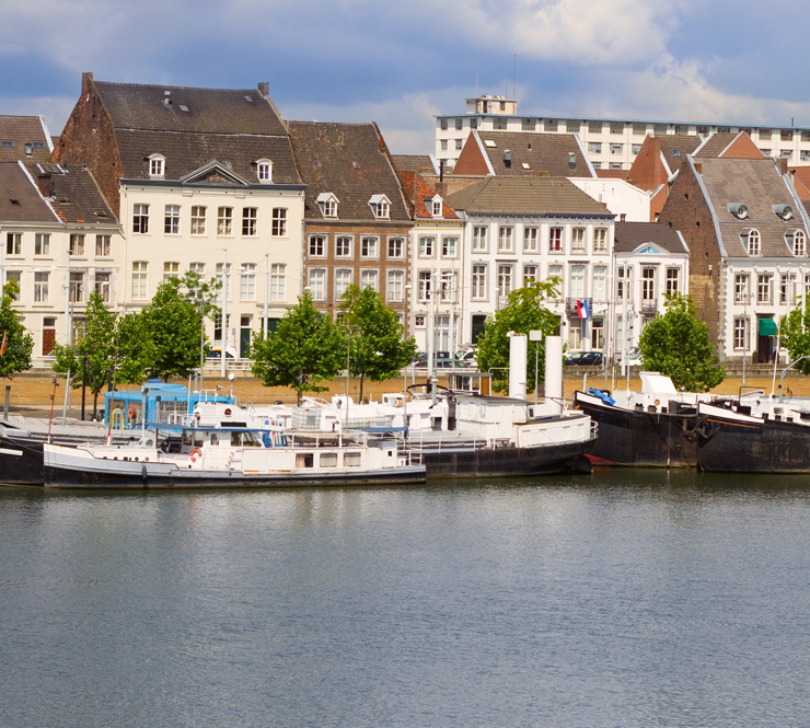 Landscape shot of buildings and boats along the Meuse River in Maastricht, Netherlands.