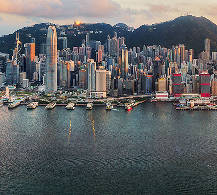 Aerial shot of Victoria Harbor and Hong Kong skyline at sunset. 