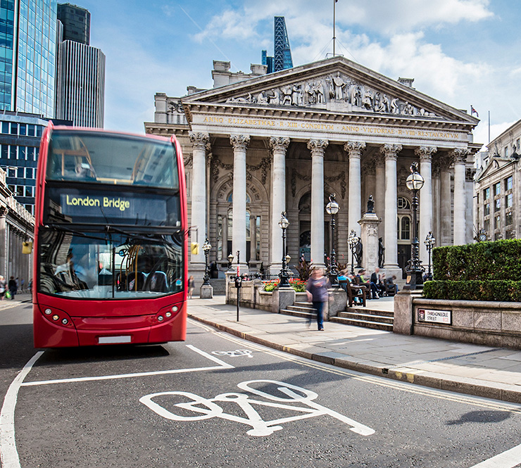 Bus waiting in front of the London Stock Exchange on a sunny day.