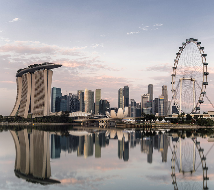 View of Marina Bay Sands, the flyer and Singapore skyline reflecting in the water at dawn. 