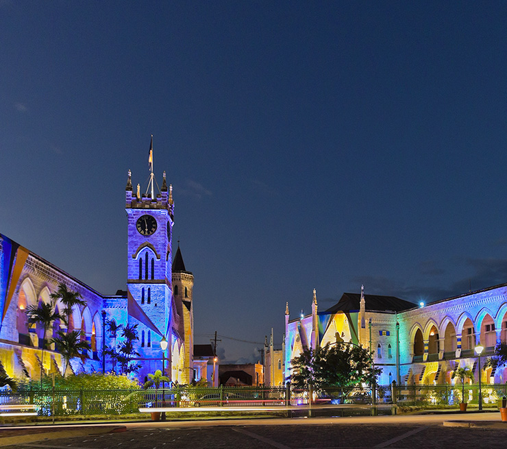 Yellow, blue, pink, and green colors lighting up the Parliament Building at night in Bridgetown, Barbados. 