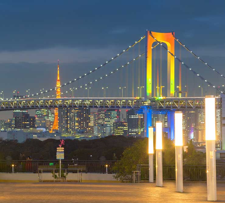 Colorfully lit Rainbow bridge and Tokyo Tower view at sunset from Odaiba, Tokyo.