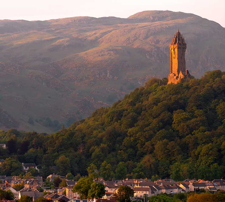 A large European castle upon a hill, at sunset 