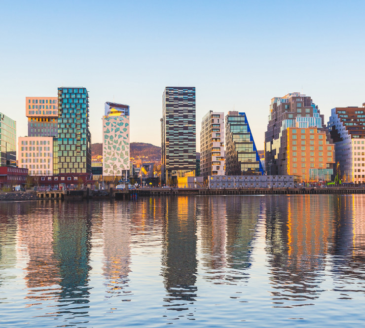 View of modern Oslo buildings, reflecting off the water at sunrise.