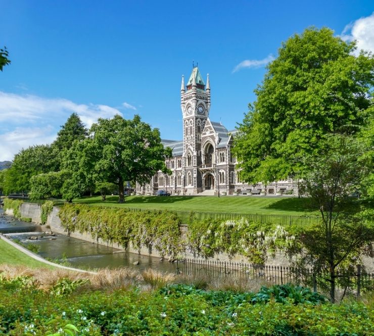 Tall building surrounded by trees on a clear sunny day in Dunedin, New Zealand