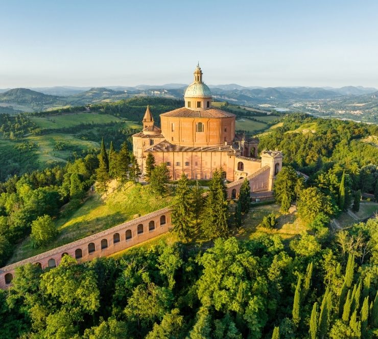 Aerial view of a sunrise-lit chapel a grass-covered valley in the background