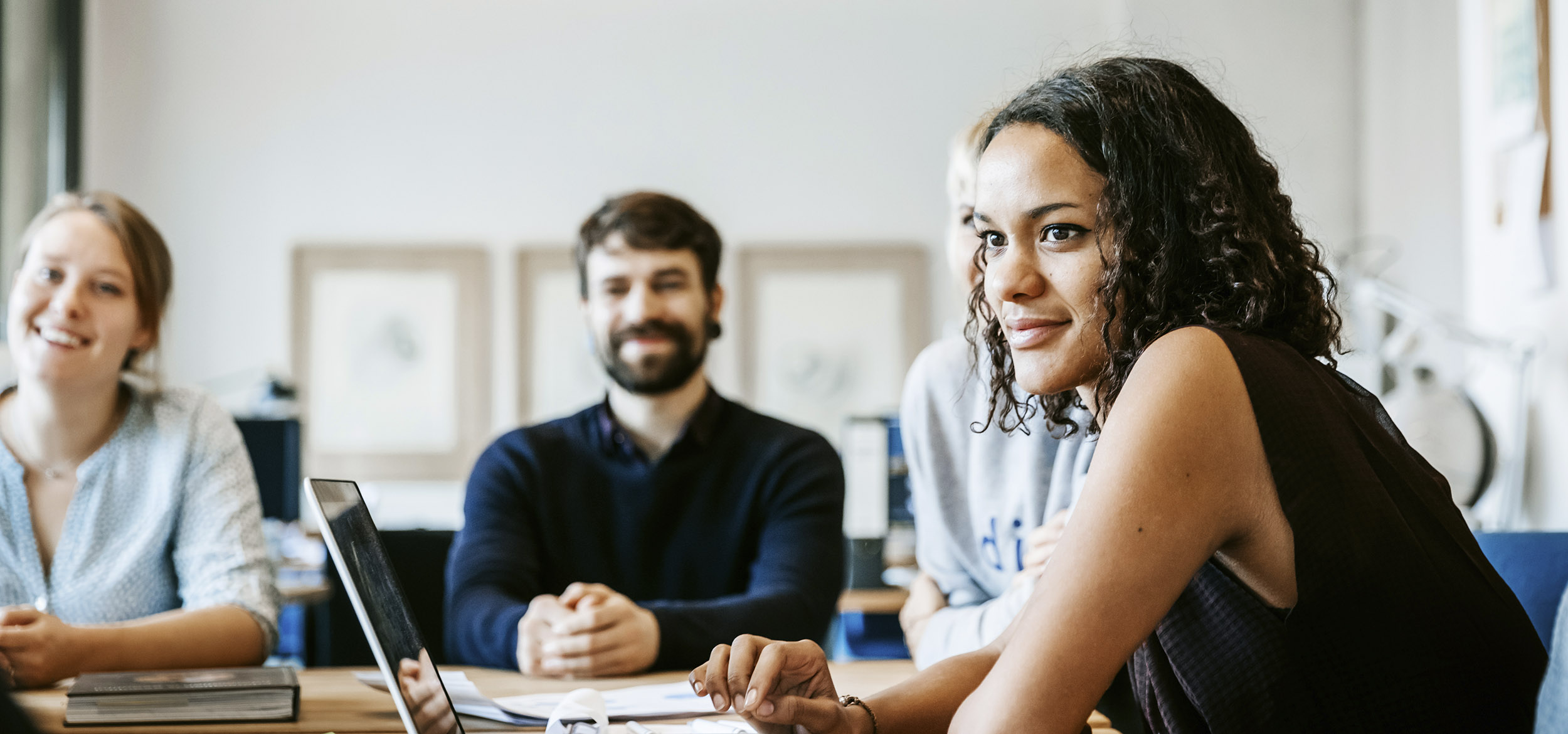 Coworkers gathering around the conference room table for a kickoff meeting in Berlin, Germany