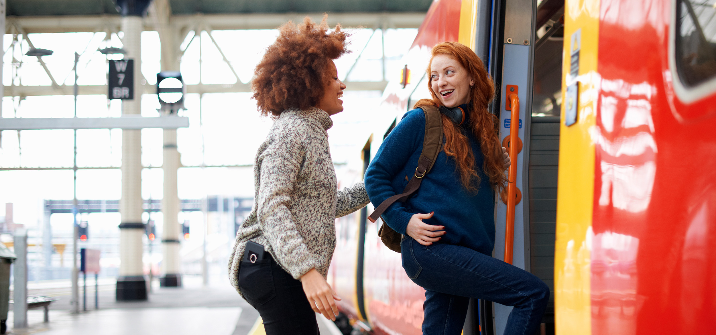 Two people boarding a train in England, smiling and laughing with each other.