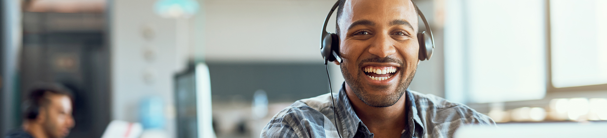 Man with headset smiling at camera in call center