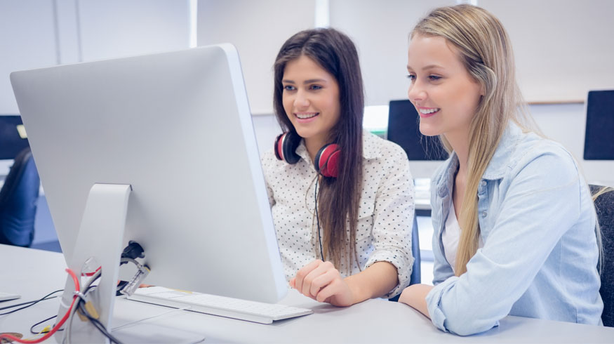 Two students sitting next to each other and looking at a computer. 