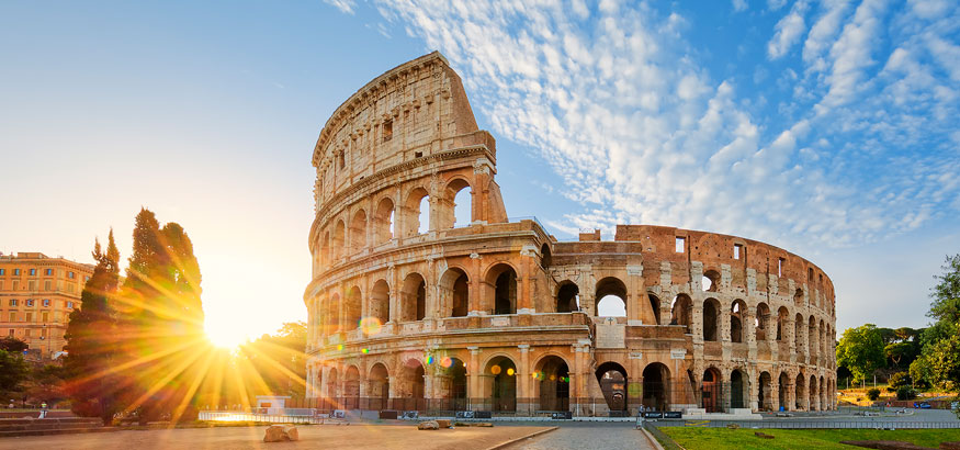 The sun rises behind the Colosseum on a beautiful day in Rome, Italy.