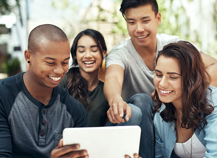 Shot of a diverse group of young men and women using a digital tablet together on campus