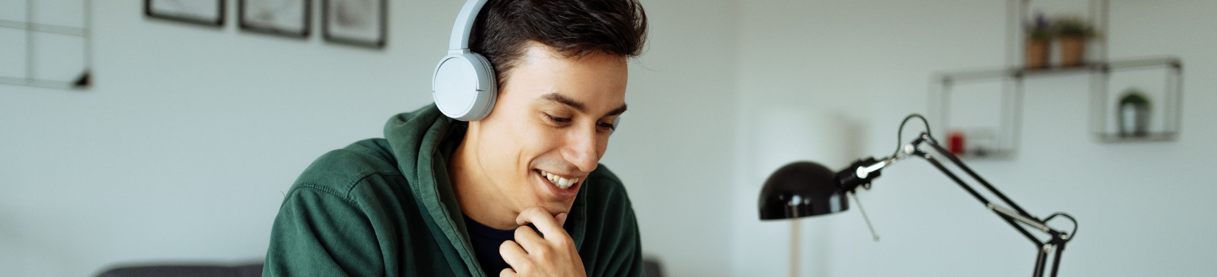Student wearing headphones looking down at his computer offscreen.