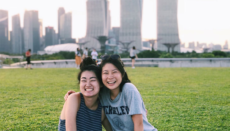 Two students smile with arms around each other in Singapore.