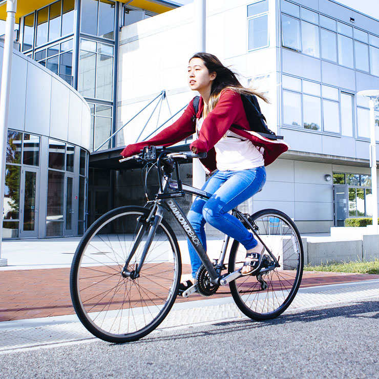 Woman rides her bike on campus.