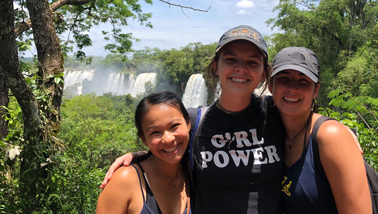 Gabrielle Dimick of UC Berkeley and friends smile at Iguazú Falls, Misiones Province, Argentina, with waterfalls in the background.