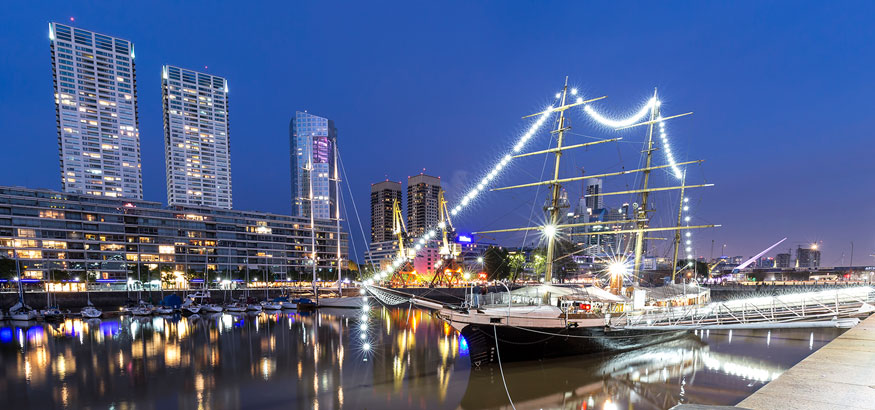 A yacht glides by under a blue sky in the evening in Puerto Maderoat in Buenos Aires, Argentina.