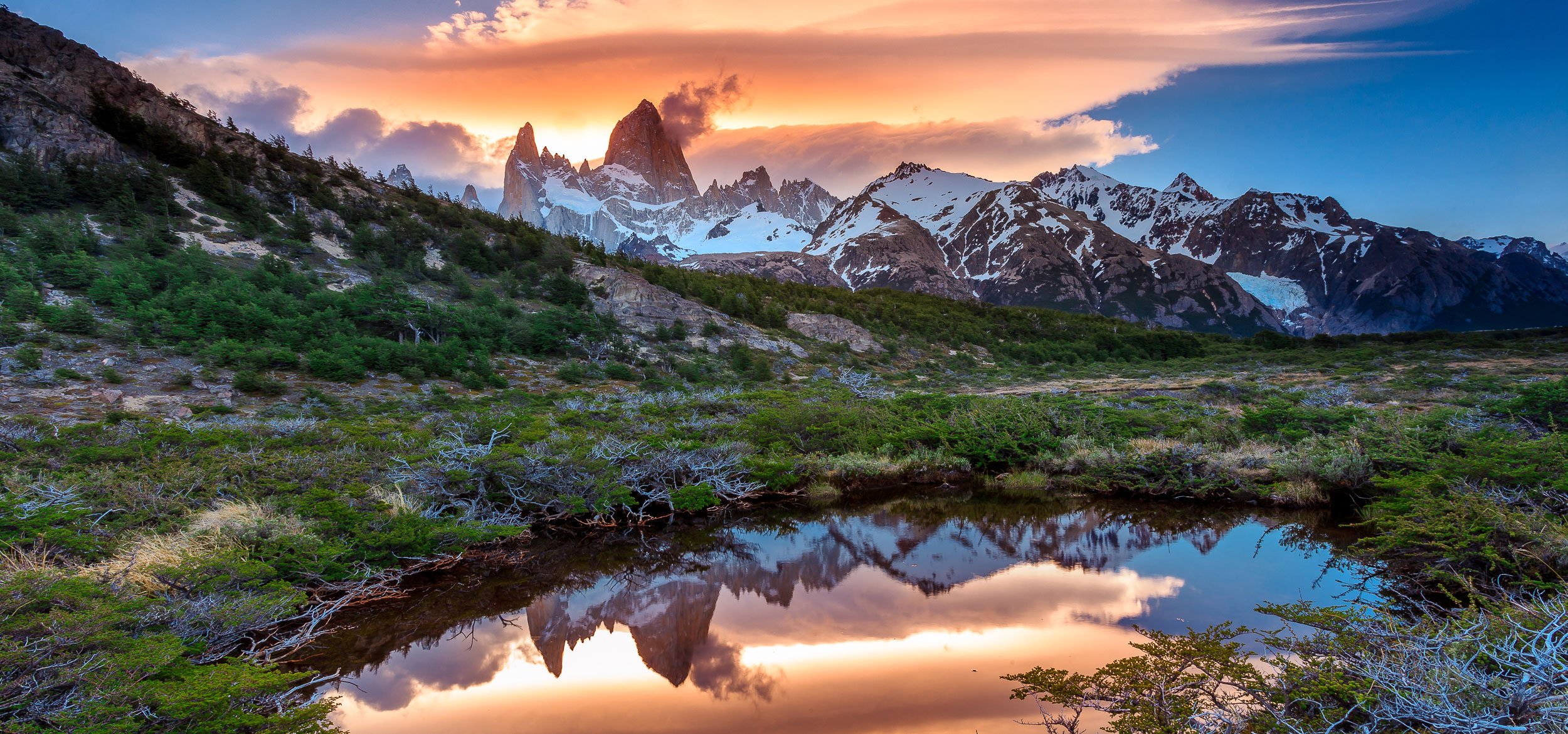 A sunset view of Mt Fitz Roy with a reflection in a grassy pond in Los Glaciares National Park, Argentina.