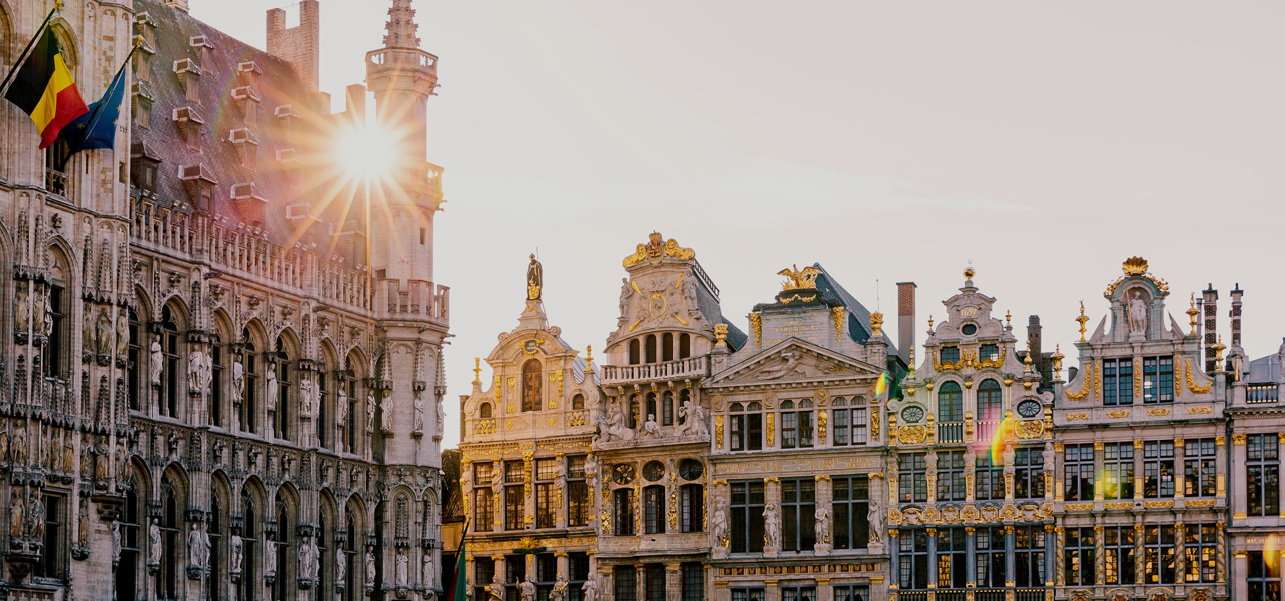 Sun shining through historic buildings at the Grand Place square in Brussels, Belgium.