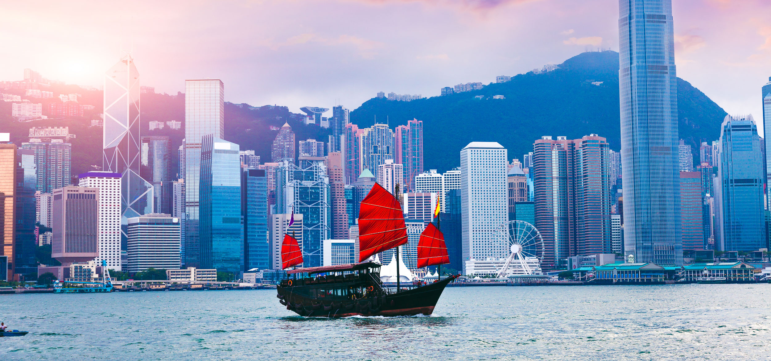 A junk boat with red, square sails crossing the Hong Kong Harbor in Hong Kong. 