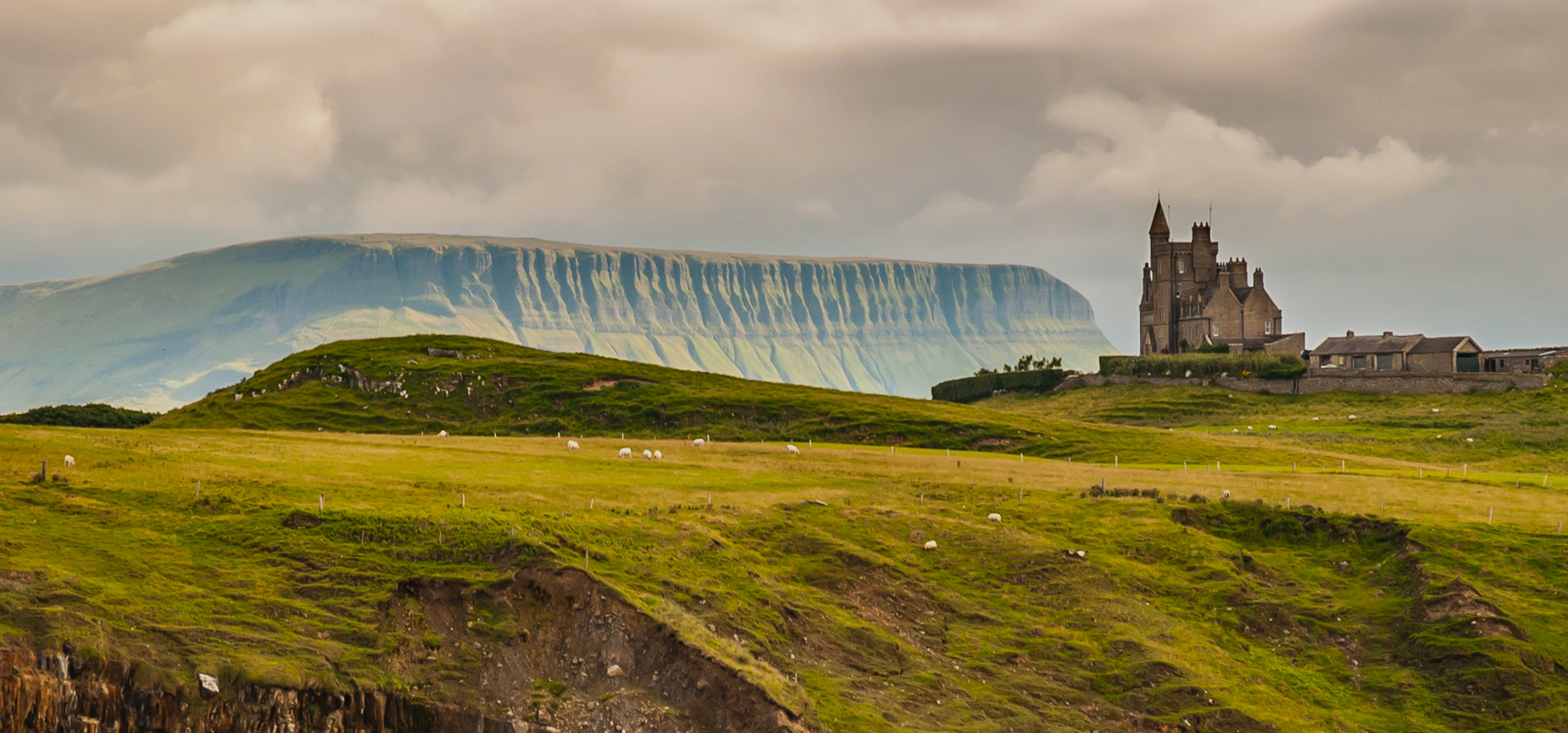 Scenic view of rugged green landscape and cliffs around Classiebawn Castle, in County Sligo, Ireland.