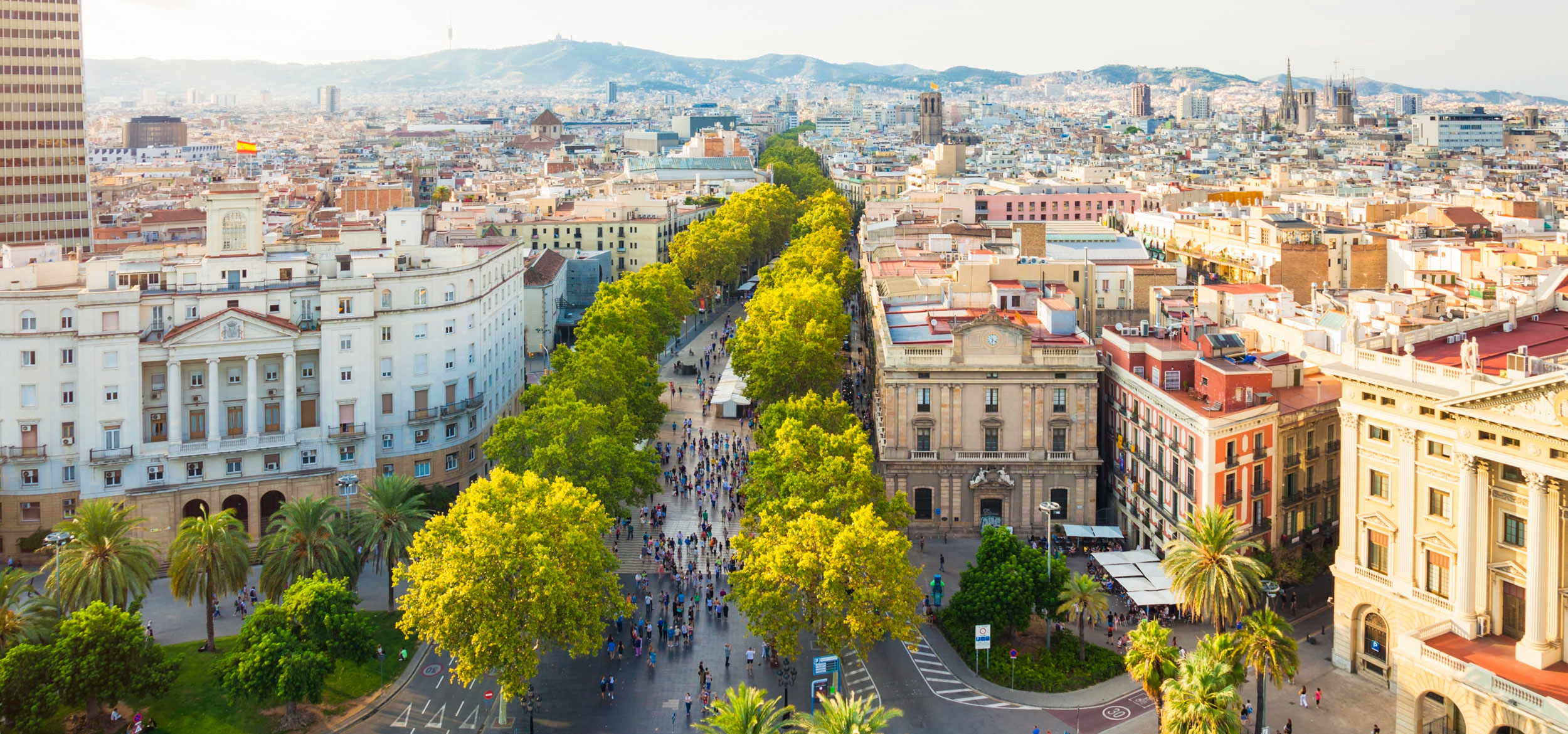 Aerial cityscape shows the landmark La Rambla, a large boulevard which runs through the heart of the city center in Barcelona, Spain. 