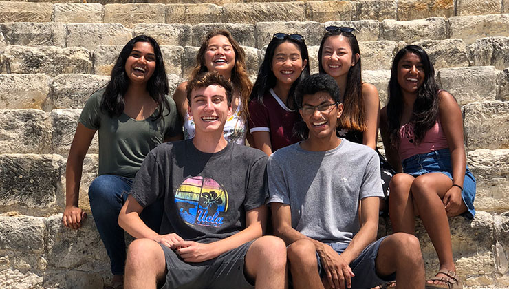 Alvina Liang of UC Los Angeles and friends sit on the steps of some ruins in Cyprus smiling.