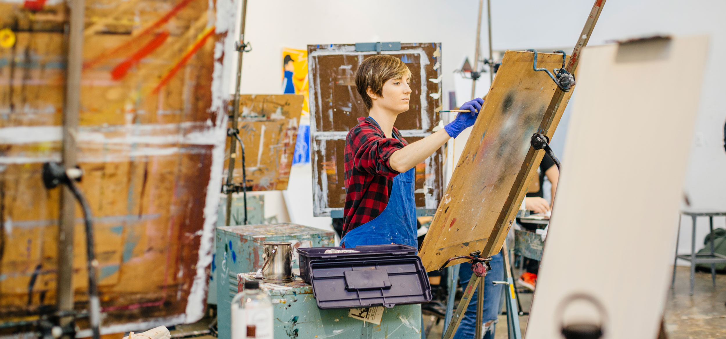 UC student practices painting techniques in an art studio. 