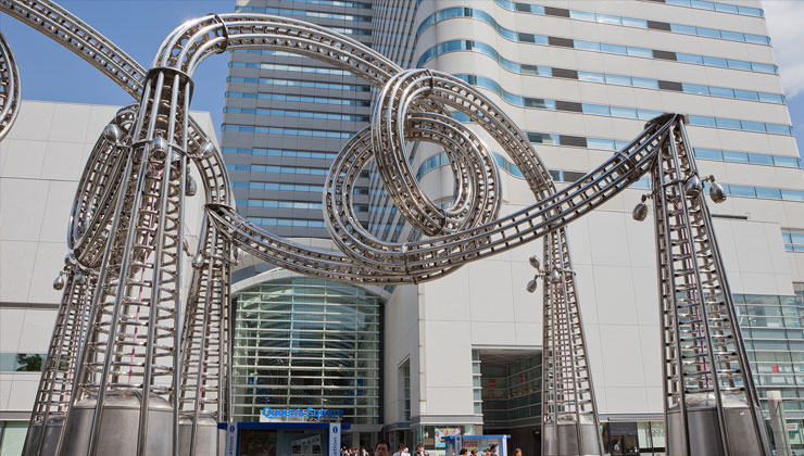 Pedestrians walk under a shiny metal sculpture that resembles a twisting, turning roller coaster at the Queen’s Square, a major shopping mall in Yokohama, Japan.