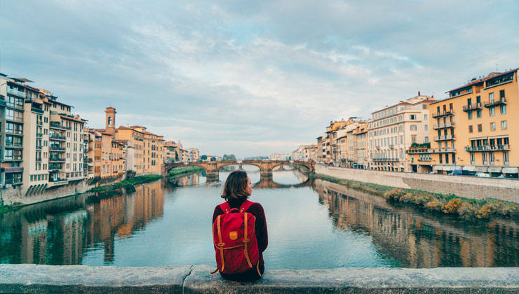 Student enjoys the view of Arno River and buildings from Ponte Veccio Bridge in Florence, Italy.