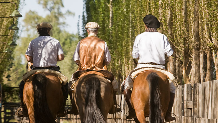 Three men on horses on a ranch.