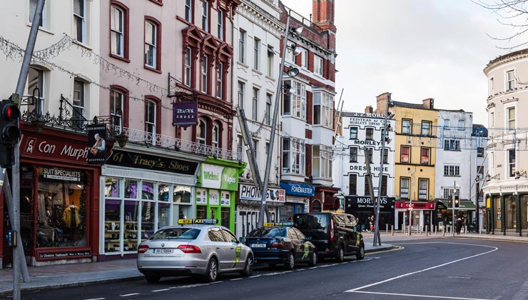 View of St. Patrick's Street with cars and colorful buildings in Cork, Ireland. 