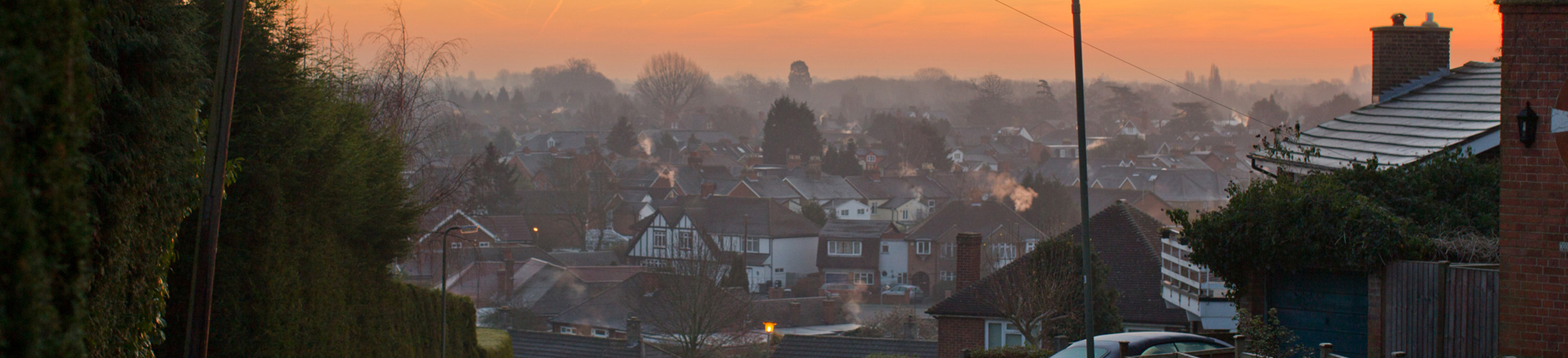  Early morning mist and orange sky over houses, Egham, England