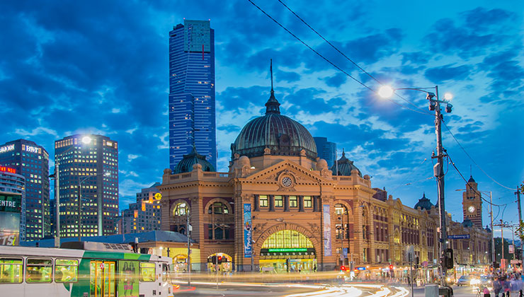 Flinders Street Station in Melbourne at night with a Melbourne tram in the foreground. 