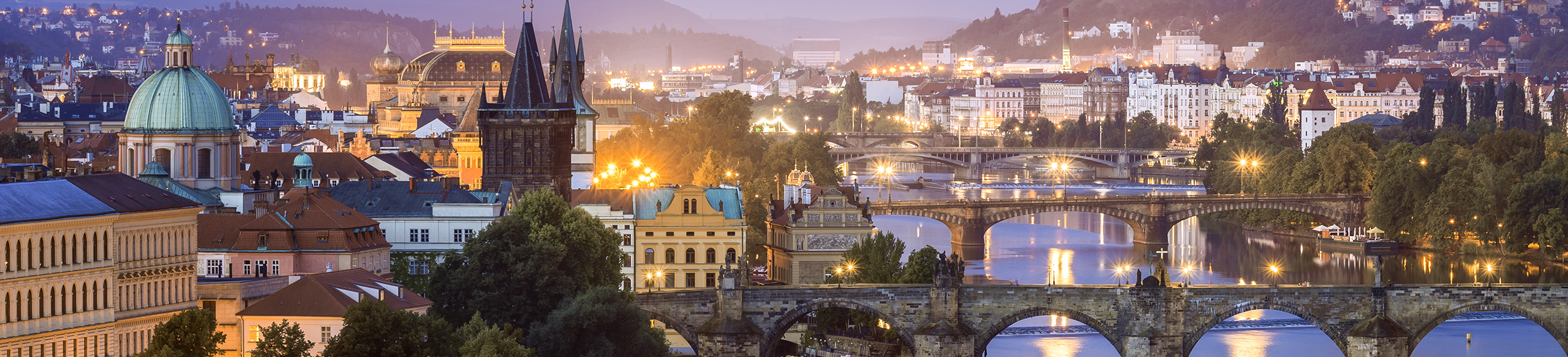 View above Prague just before sunrise, including Charles Bridge and Vltava River.