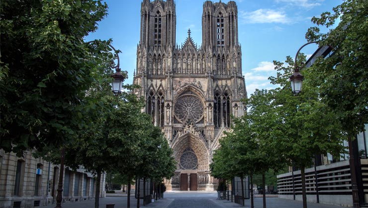 View of Reims Cathedral with green trees in Reims, France. 