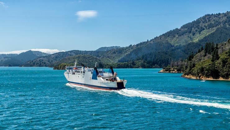 View of a boat on the water and green mountains in the background. 