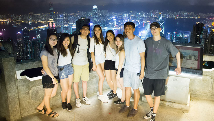 UC Santa Cruz student Karson Kwan and friends pose at The Peak in Hong Kong with city lights in the background.