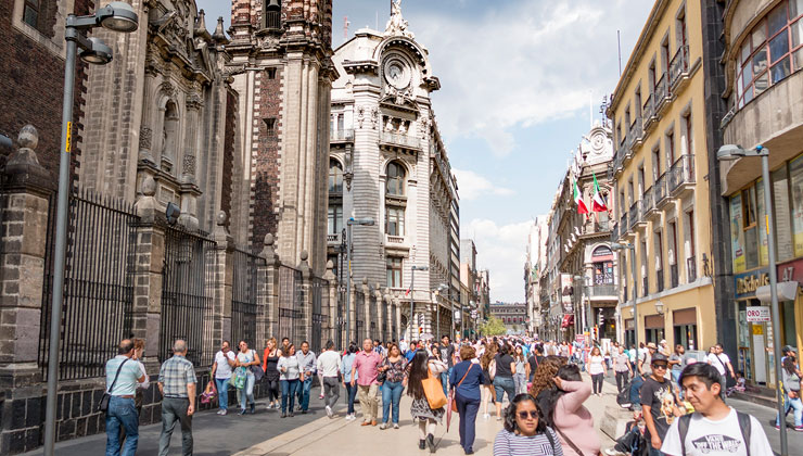Tourists walk the streets in the Historic Center of Mexico City on a sunny day.