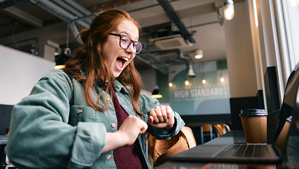 delighted student reading screen on laptop