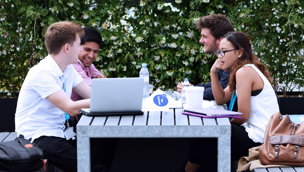 Group of young people sitting at a table with a computer discussing application