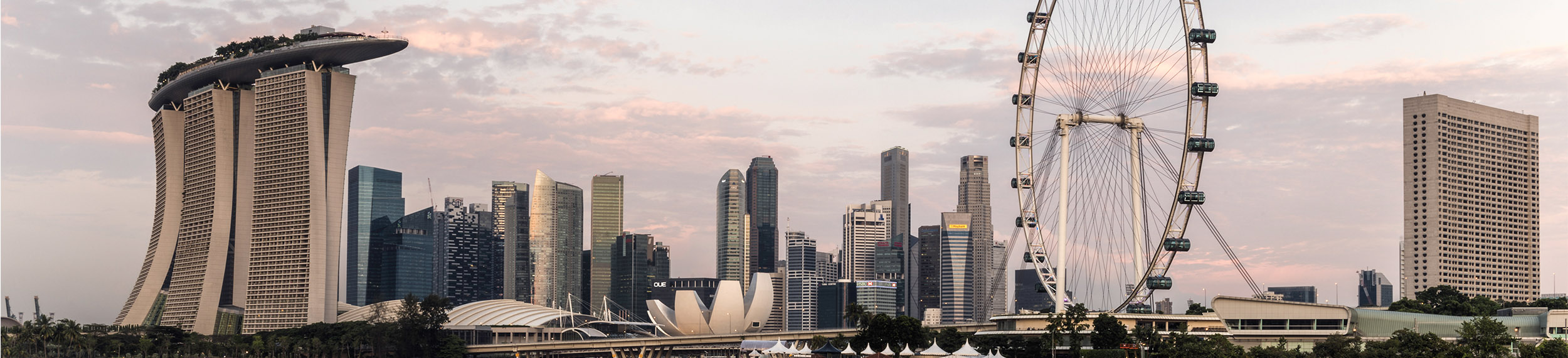 View of Marina Bay Sands, the flyer and Singapore skyline reflecting in the water at dawn. 
