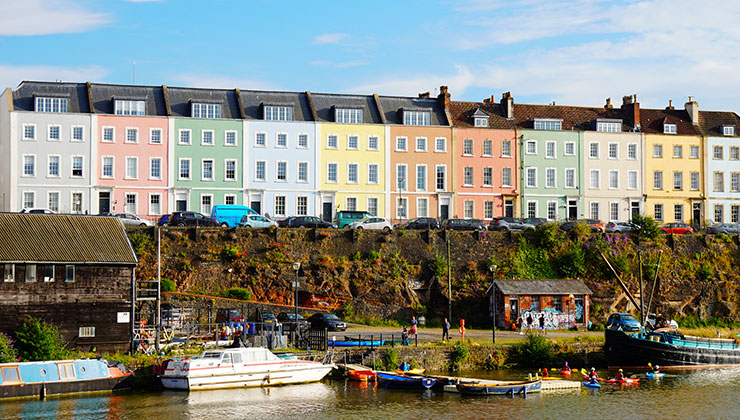 A row of pastel colored houses overlooking the waters of the Bristol Harbour.