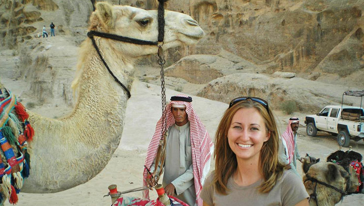 Female student standing next to a camel in Amman, Jordan.