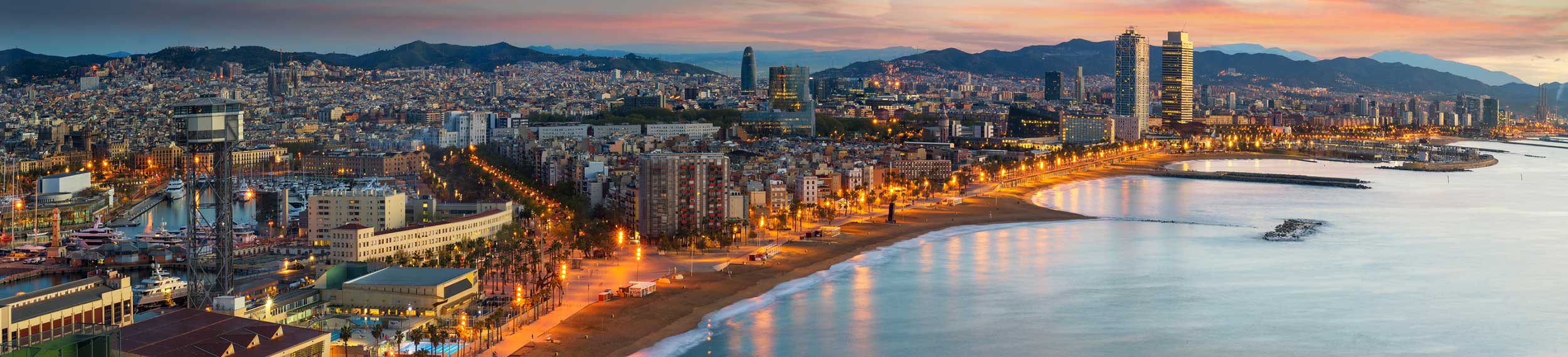 Aerial view of Barcelona cityscape and beach at sunrise.