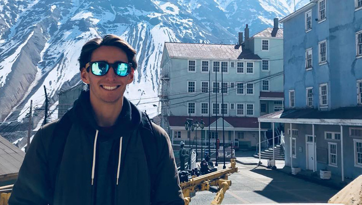 Austin Stahl of UC Santa Barbara smiles with snow-covered mountains in the background on a field trip to Sewell, Chile.