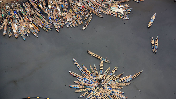 An aerial shot of colorful fishing boats form interesting patterns against the grey water. 