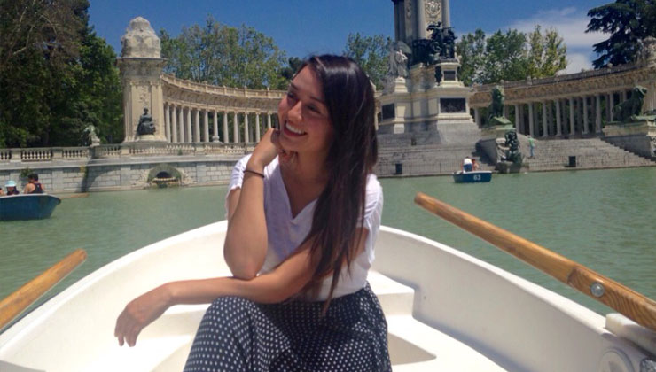 A student posing on a boat with a view of the Monument to Alfonso XII sculpture in Buen Retiro Park, Madrid.