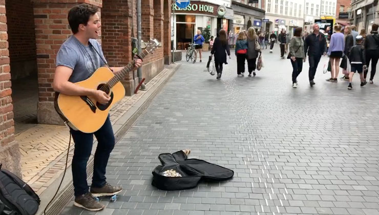 Student plays acoustic guitar on the street in Copenhagen, Denmark.
